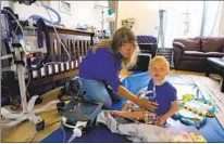  ?? NELVIN C. CEPEDA U-T ?? Ali Tebbs checks on her son Samuel’s feeding tube. Samuel is fed formula through a feeding tube two to three times a day.