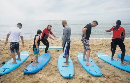  ?? KRISTEN ZEIS/STAFF ?? Charles Lutz, instructor with VB Surf Sessions, teaches participan­ts how to pop-up during lessons hosted by the Wounded Warrior Project.