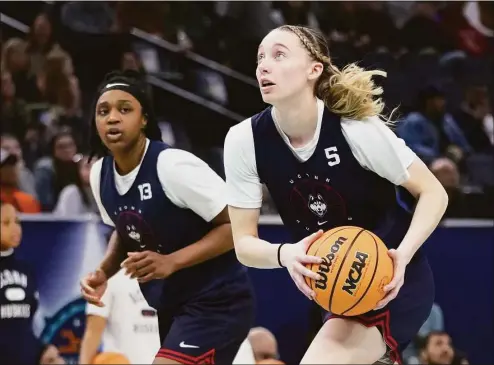  ?? Charlie Neibergall / Associated Press ?? UConn’s Paige Bueckers and Christyn Williams run a drill during a practice session on Saturday during the lead up to the NCAA national championsh­ip game.
