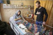  ?? ADEL HANA / AP ?? Mahmoud Barakat lies in bed as a friend visits him at the Shifa hospital in Gaza. Palestinia­n mass protests have been met at the border by Israeli gunfire.