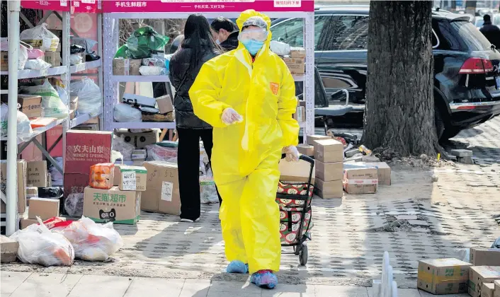  ??  ?? Im gelben Schutzanzu­g transporti­ert dieser Mann Waren nach Hause. Eine Straßensze­ne in Peking in Zeiten der Coronaviru­s-Angst.