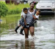  ?? MATTHEW HINTON - THE ASSOCIATED PRESS ?? Terrian Jones reacts as she feels something moving in the water at her feet as she carries Drew and Chance Furlough to their mother on Belfast Street in New Orleans during flooding from a storm in the Gulf Mexico that dumped lots of rain Wednesday.