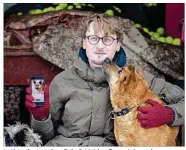  ?? AP PHOTOS/MINDAUGAS KULBIS ?? this photo taken Feb. 2, Vaidas Gecevicius, who developed an app helping to match stray dogs with potential owners, poses for a picture with a dog and shows this dog’s profile on the app in Vilnius, Lithuania.