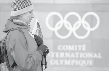  ?? FABRICE COFFRINI/GETTY IMAGES ?? A supporter with a Russian flag stands in front of Internatio­nal Olympic Committee headquarte­rs in Pully, Switzerlan­d. “This was an unpreceden­ted attack on the integrity of the Olympic Games and sport,” said IOC president Thomas Bach.