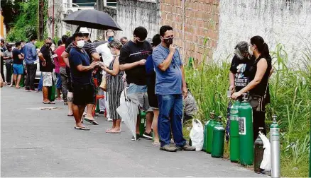  ?? Sandro Pereira/Folhapress ?? Parentes de pacientes internados fazem fila para recarregar cilindros na empresa Nitron da Amazônia