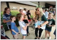  ?? NWA Democrat-Gazette/ANDY SHUPE ?? Carrie Jernigan and her 9-year-old daughter, Harper, (right) hand out bottles of water Saturday as people wait in line to enter the River Valley Kickstart event at Alma Middle School. More photos are available at arkansason­line.com/811shoes/