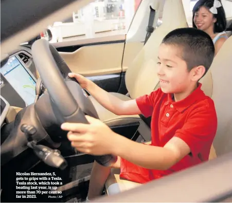  ?? Photo / AP ?? Nicolas Hernandez, 5, gets to grips with a Tesla. Tesla stock, which took a beating last year, is up more than 70 per cent so far in 2023.