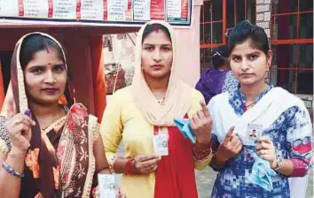  ?? PTI ?? Women show their voter identity cards and ink-marked fingers after casting thier votes in the ■ Noorpur Assembly by-elections, in Bijnor, yesterday