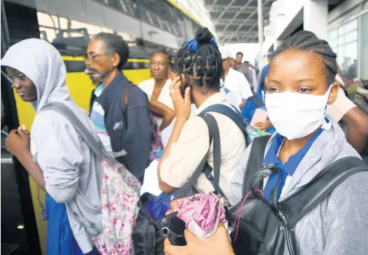  ?? FILE ?? A high-school student wears a cloth face mask at the Half-Way Tree Transport Centre on Wednesday, March 11, a day after the first coronaviru­s case was recorded in Jamaica. Some administra­tors have ordered that students only wear branded masks to school.