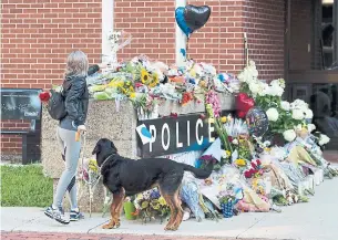  ?? ANDREW VAUGHAN/THE CANADIAN PRESS ?? Flowers are placed on a makeshift memorial outside the police station in Fredericto­n on Saturday. Two city police officers were among four people who died in the shooting.