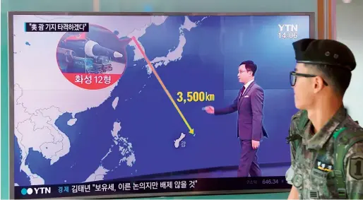  ?? AFP ?? A South Korean soldier walks past a television screen showing a graphic of the distance between N. Korea and Guam at a railway station in Seoul on Wednesday. —