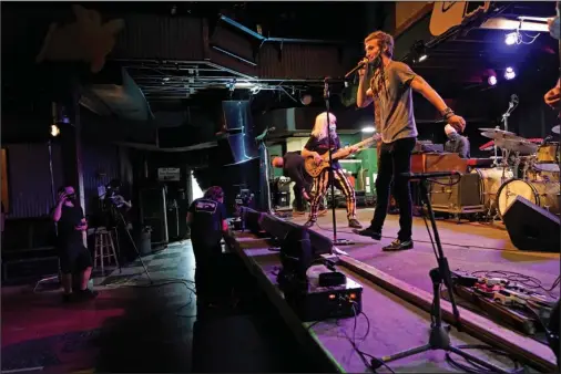  ?? The Associated Press ?? GOING UP TO 11: David Shaw, foreground, frontman for the band The Revivalist­s, performs with actor Harry Shearer, co-author and character in the movie “This Is Spinal Tap,” as they record a video stream concert with the band Galactic on Oct. 26 inside an empty Tipitina’s music club, in New Orleans. Music clubs all over the nation — pop culture icons like the Troubadour in West Hollywood, the Bluebird Cafe in Nashville, The Bitter End in New York’s Greenwich Village — are shuttered due to the coronaviru­s. And owners fear for the future of their businesses and of a musical way of life.