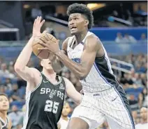 ?? JOHN RAOUX/AP ?? The Magic’s Jonathan Isaac, right, goes up for a shot past the San Antonio Spurs’ Jakob Poeltl on Friday at Amway Center.