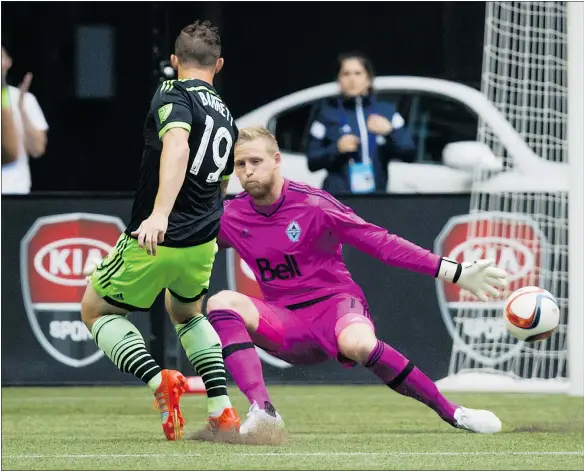  ?? — THE CANADIAN PRESS ?? Seattle’s Chad Barrett scores on Vancouver goalie David Ousted during the first half of Saturday’s game at B.C. Place.