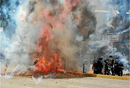  ?? PHOTO: REUTERS ?? Flames erupt as clashes break out near security forces members while the Constituen­t Assembly election is being carried out in Caracas, Venezuela,.