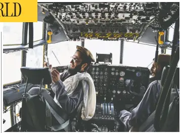  ?? WAKIL KOHSAR / AFP VIA GETTY IMAGES ?? Taliban fighters sit in the cockpit of an Afghan air force aircraft at the airport in Kabul on Tuesday,
after the United States pulled all of its troops out of the country to bring an end to the 20-year war.