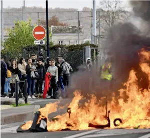  ??  ?? High school students look on as protesters burn a barricade in front of their high school during a demonstrat­ion against French government Education reforms on Tuesday in Bordeaux. —