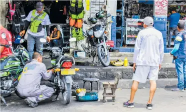  ?? JOHN ROBLEDO ?? Un mecánico arregla una de las motociclet­as en plena vía de la carrera 40 entre calles 44 y 42.