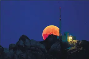  ?? CHRISTIAN MERZ/KEYSTONE ?? The moon turns red during a total lunar eclipse, behind the Saentis in Luzern, Switzerlan­d, Friday.