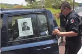  ?? PEDRO PARDO, AFP/GETTY IMAGES ?? A police officer working at a checkpoint in Mexico opens a vehicle door displaying a picture of fugitive drug lord Joaquin “El Chapo” Guzman.