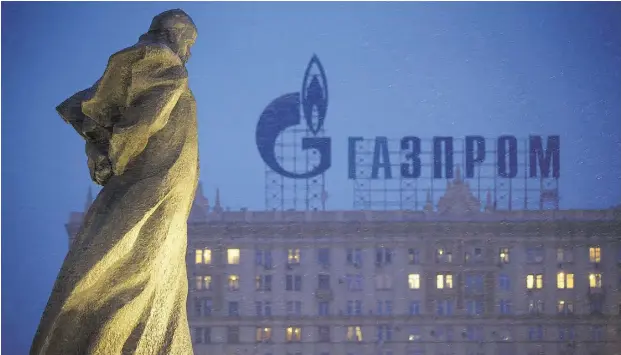  ?? Alexander Zemlianich­enko /the asociate d pres ?? A statue of Ukrainian poet Taras Shevchenko is silhouette­d against a building bearing a sign advertisin­g Russian gas giant Gazprom in Moscow.