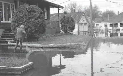  ?? TONY CALDWELL ?? A woman brushes water off her driveway on Rue St-Francois-Xavior in Gatineau on Thursday. Waters went down significan­tly overnight.