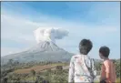  ?? Binsar Bakkara The Associated Press ?? Youths watch Thursday as Mount Sinabung spews volcanic materials during an eruption in Karo, North Sumatra, Indonesia.