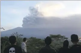  ?? PHOTOS BY FIRDIA LISNAWATI — THE ASSOCIATED PRESS ?? Villagers watch the Mount Agung volcano erupting during sunrise in Karangasem, Bali island, Indonesia on Sunday. 21 internatio­nal flights were canceled stranding about 2,000 travelers at the airport. About 25,000 have been unable to return to their...