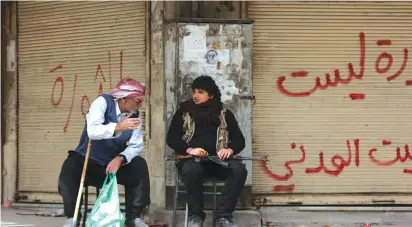  ?? (Reuters/Khalil Ashawi) ?? MEN TALK in front of closed shops in Afrin, Syria, in 2018.