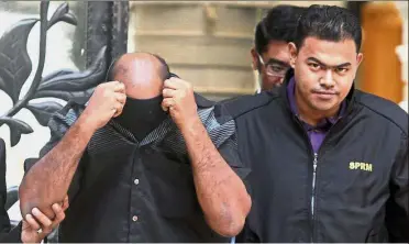  ??  ?? Under suspicion: The Melaka district CID chief concealing his face after being released on RM50,000 bail by a magistrate’s court in Putrajaya.