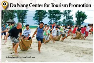  ??  ?? Visitors take part in a beach sack race