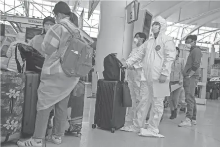  ?? MARY ALTAFFER/AP ?? Passengers wear safety gear to fend off coronaviru­s as they wait in line to check in for their flights March 24 at JFK airport in New York.