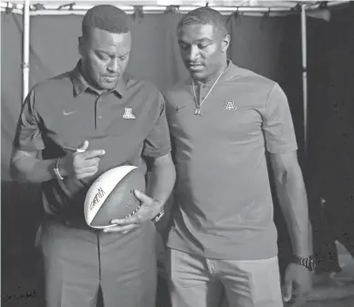  ?? JAE C. HONG/AP ?? Arizona quarterbac­k Khalil Tate (right) and coach Kevin Sumlin sign a football at Pac-12 football media day in Los Angeles on July 25.