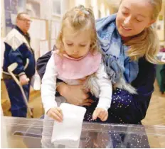  ?? — Reuters ?? A woman with a child cast her vote at a polling station in Warsaw on Sunday.