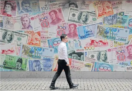  ?? AP ?? A man walks past a money exchange shop in Central, the key business district of Hong Kong.