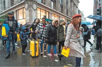  ?? AFP ?? Shoppers carry packages in central London. A spike in workplace absenteeis­m, lower productivi­ty, sliding travel, disrupted supply chains and reduced trade and investment will likely be the lead causes of loss to the global economy.