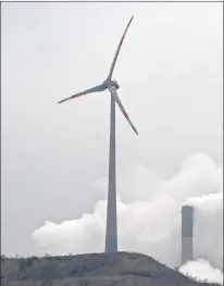  ?? AP FILE ?? A wind turbine overlooks a coal-fired power station in this 2014 photo.