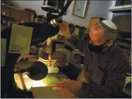  ??  ?? Klaus Rotzscher stamps a book with gold leaf. At 65, he plans to retire from the Pettingell Book Bindery, which he has owned since 1994.