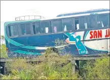  ??  ?? La rueda trasera del transporte de pasajeros hundida entre las tablas del precario puente de madera.