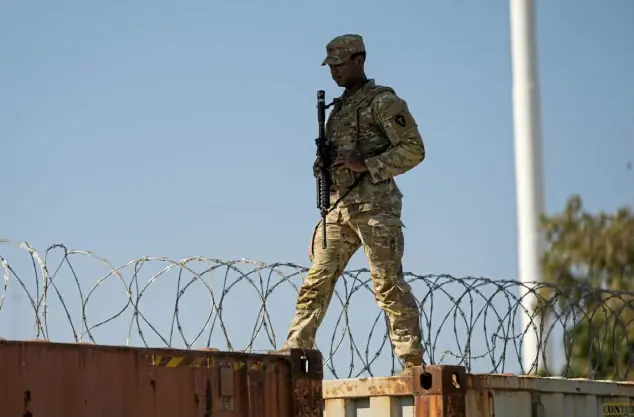  ?? Associated Press ?? A guardsman walks over rail cars with concertina wire along the Texas-Mexico border.