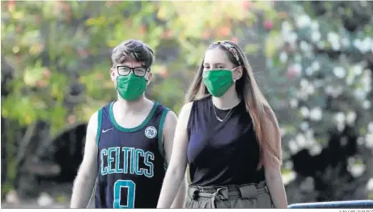  ?? JUAN CARLOS MUÑOZ ?? Dos jóvenes pasean por Sevilla haciendo uso de la mascarilla obligatori­a.