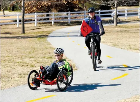  ?? STAFF PHOTO MICHAEL WOODS ?? Dimitri Clark of Fayettevil­le and his father, Jimmie Clark, ride their bikes around Lake Fayettevil­le on Sunday afternoon. Dimitri always wanted to ride bikes but struggled because of cerebral palsy.