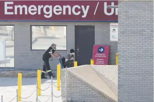  ?? ( Shannon VanRaes/ Reuters) ?? A PARAMEDIC PUSHES a man towards St. Boniface Hospital, in Winnipeg, Manitoba earlier this month, a site which has seen a lot of coronaviru­s patients according to local media.