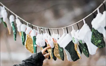  ?? ADREES LATIF/REUTERS PHOTO ?? A boy touches stockings, representi­ng those killed in the Dec. 14 shooting at Sandy Hook Elementary School, on Christmas morning in Sandy Hook Village in Newtown, Conn. The holiday has helped some people cope with their grief.