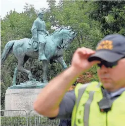  ?? PHOTOS BY MIKE TRIPP/STAUNTON NEWS LEADER ?? An officer stands near the much-disputed statue of Robert E. Lee in Charlottes­ville, Va., on Saturday.