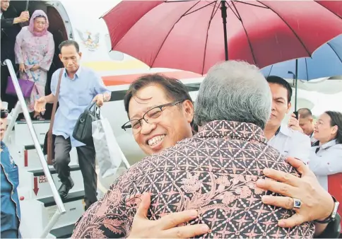  ??  ?? Abang Johari is given a warm welcome by Awang Tengah upon touching down at Limbang Airport. Juma’ani is seen standing at the entrance of the aircraft.