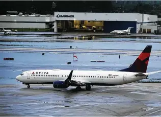  ?? Joe Cavaretta / TNS ?? A Delta passenger aircraft taxis past a flooded runway Monday at Fort Lauderdale-Hollywood Internatio­nal Airport. The flooding caused delays on one of the year’s busiest travel days.