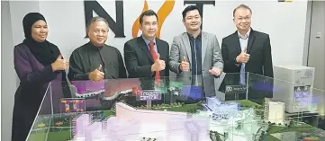  ??  ?? Voon (centre), Wong (second right) and other partners pose for a photo behind a replica developmen­t of Tropics City at NIIT College’s office in Kuching yesterday.