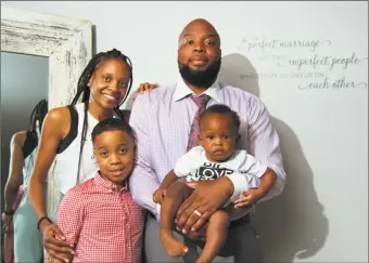  ??  ?? Stacey Pierre-Louis stands with his wife, Courtne, his son Eliah, 9, and their baby daughter Chloe, 1, at their home in Trumbull on Friday.