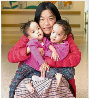  ?? — AFP ?? Successful operation: A file photo showing Zangmo holding Dawa (left) and Nima at the hospital before the surgery in Melbourne. The team of more than 20 doctors and nurses spent six hours operating on the girls, who shared a liver.